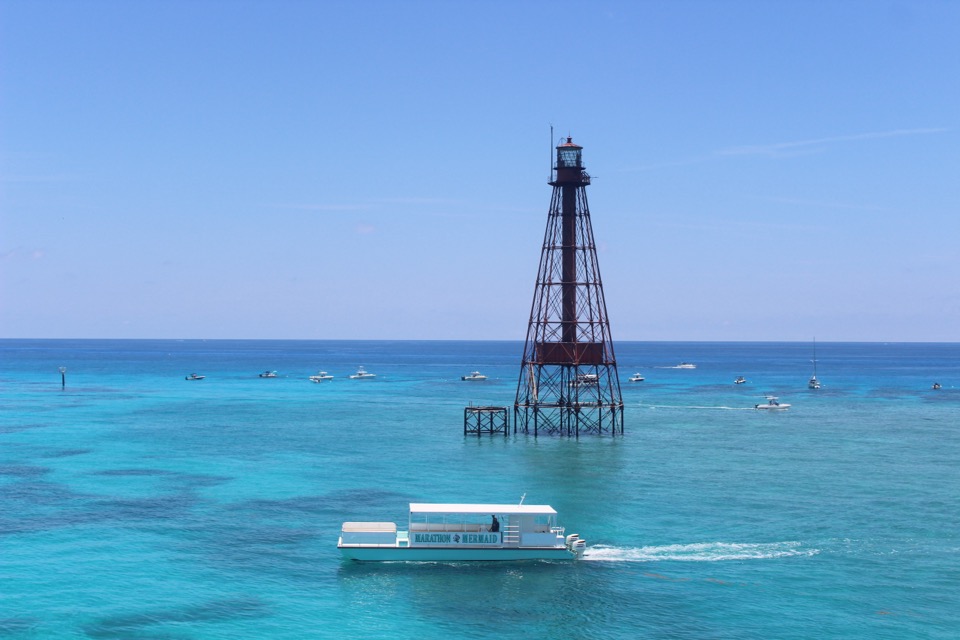 The Marathon Mermaid catamaran cruising past the Sombrero Reef lighthouse over vivid blue water