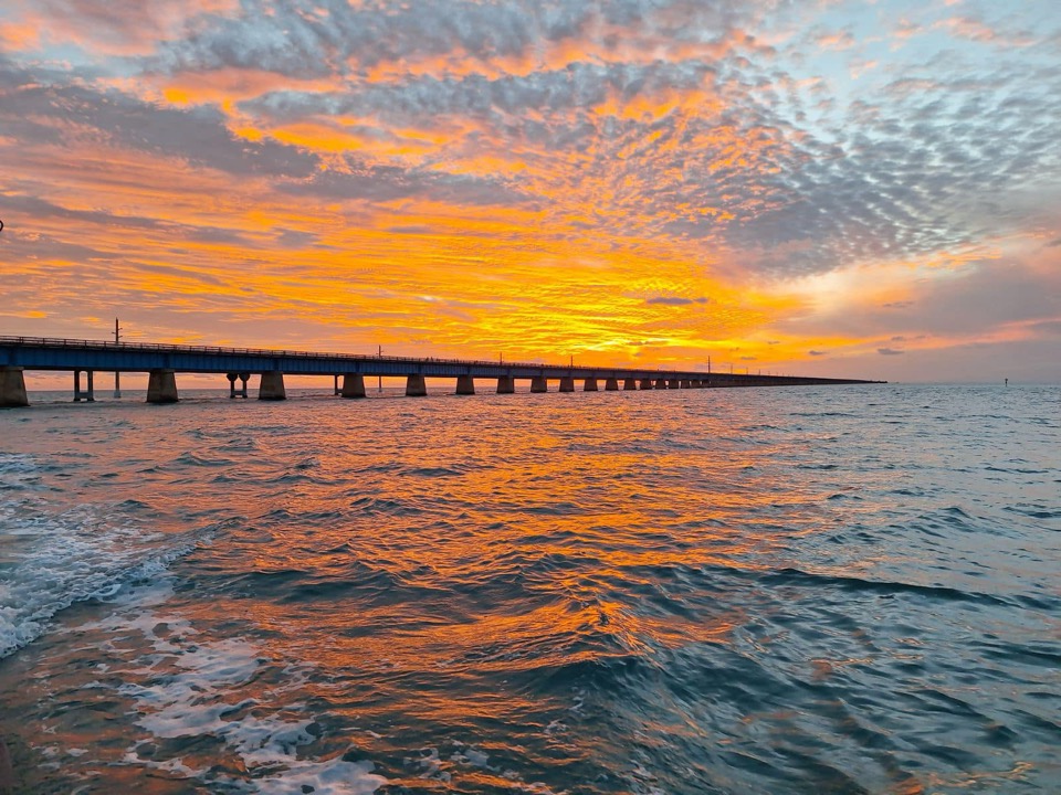 A fiery orange sunset glowing behind the Seven Mile Bridge in the Florida Keys