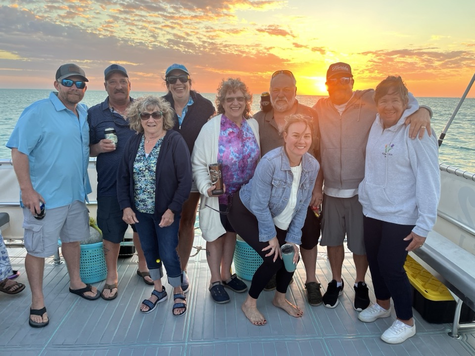 A happy group of guests together on the deck at sunset