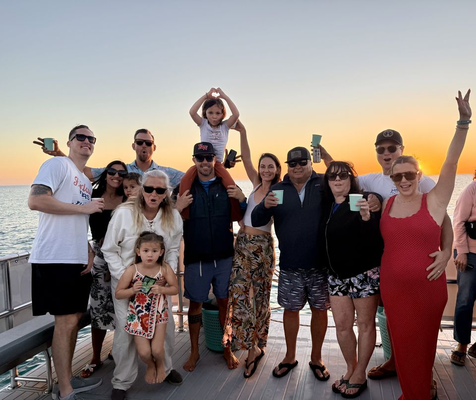 A big group of guests celebrating together on the deck at sunset