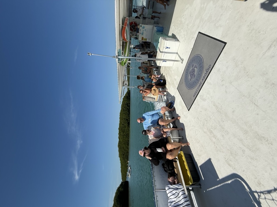 Guests seated under the shade canopy with the company logo mat on the deck