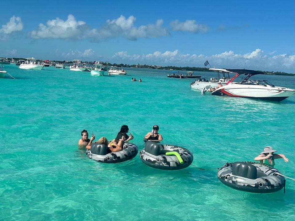 Guests floating in tubes over brilliant turquoise sandbar water