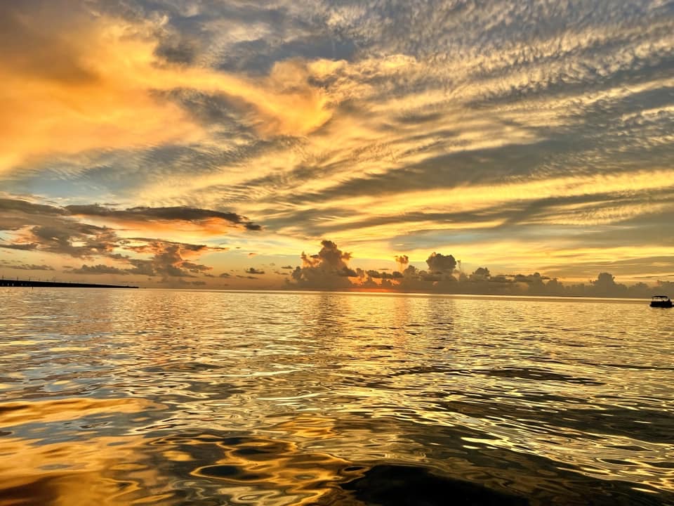 A golden streaked sunset sky mirrored on calm water