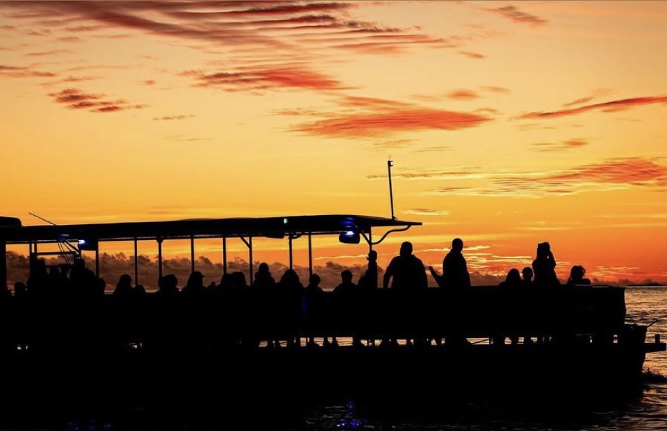 Silhouette of a packed sunset cruise catamaran against a vivid orange Keys sky