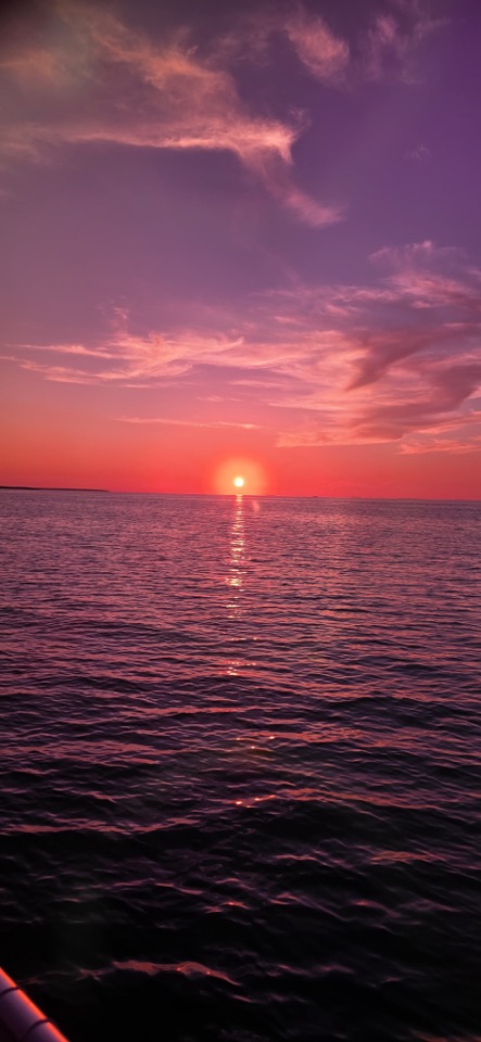 A vivid pink and purple sunset over calm open water