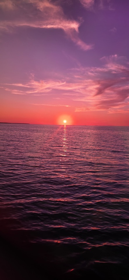 A deep purple and red sunset glowing over glassy water