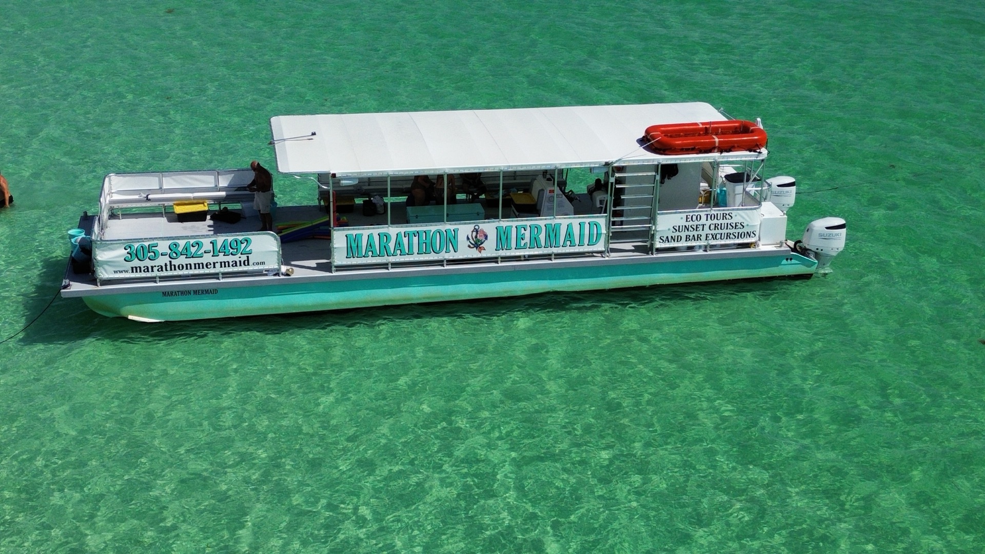 A crisp aerial of the branded Marathon Mermaid catamaran over emerald-green water