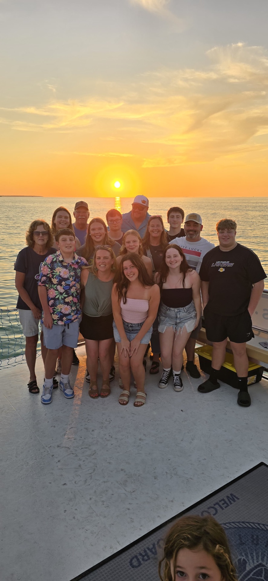 A large family group posed together on deck framed by a full golden sunset