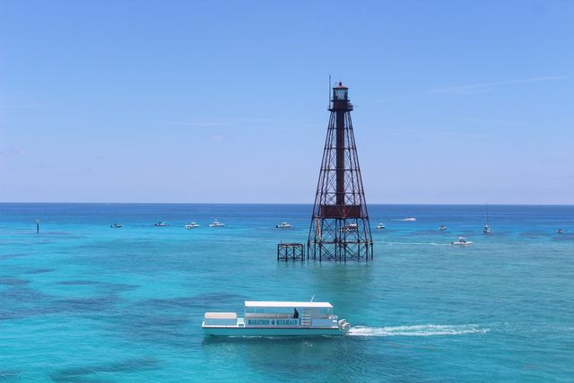 The Marathon Mermaid catamaran cruising past the Sombrero Reef lighthouse over vivid blue water