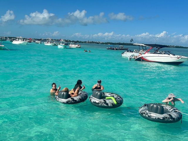 Guests floating in tubes over brilliant turquoise sandbar water