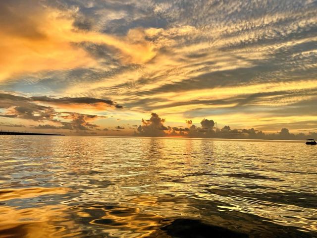 A golden streaked sunset sky mirrored on calm water