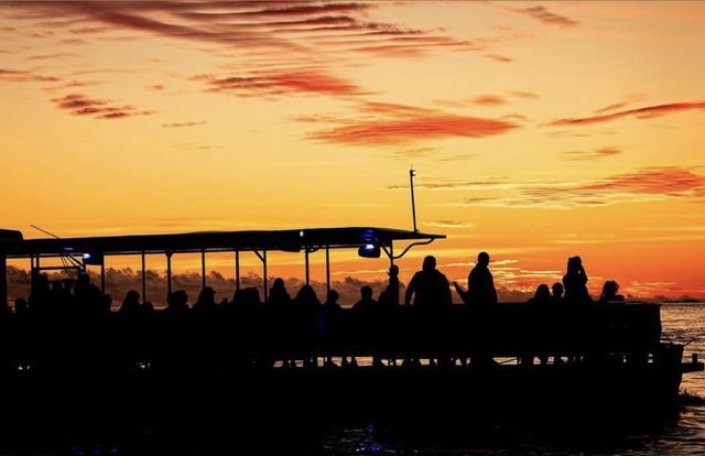 Silhouette of a packed sunset cruise catamaran against a vivid orange Keys sky