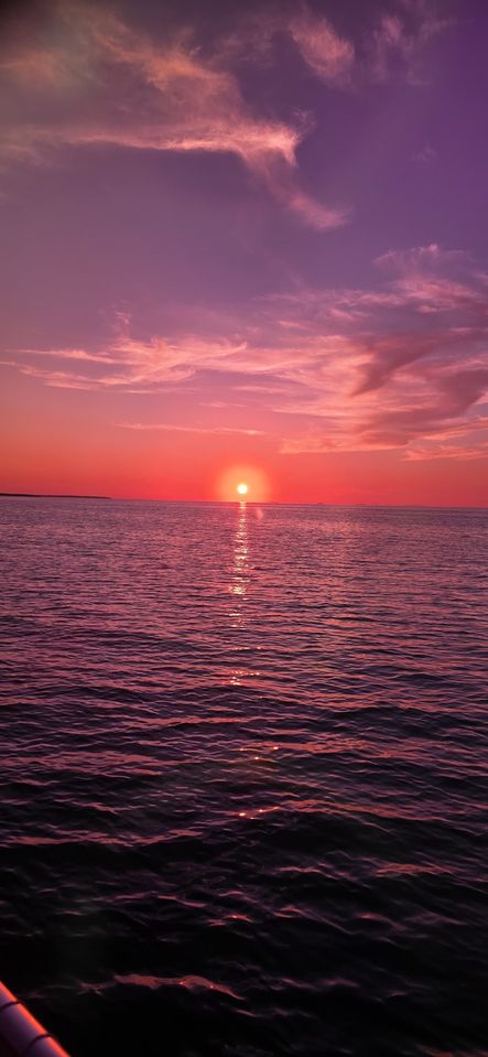 A vivid pink and purple sunset over calm open water